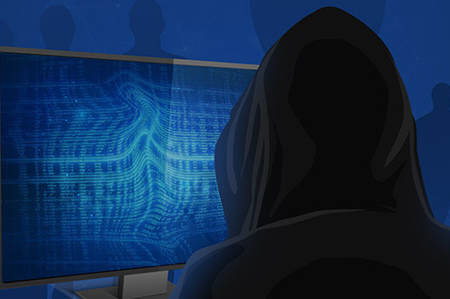 Hacker in black hoodie sitting in front of computer screen