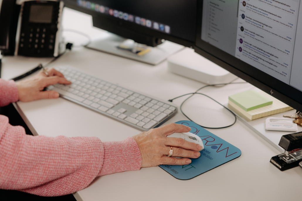 An office worker’s hands using a keyboard and mouse of a macOS system in a mixed environment.