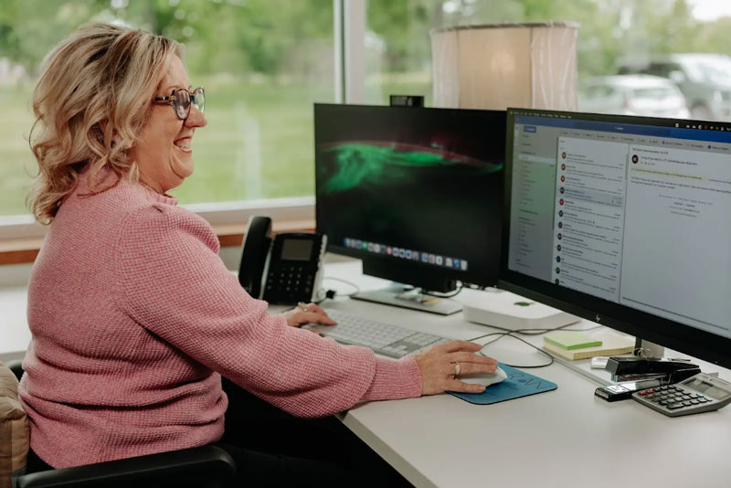 A woman using her computer mouse to view emails at work.