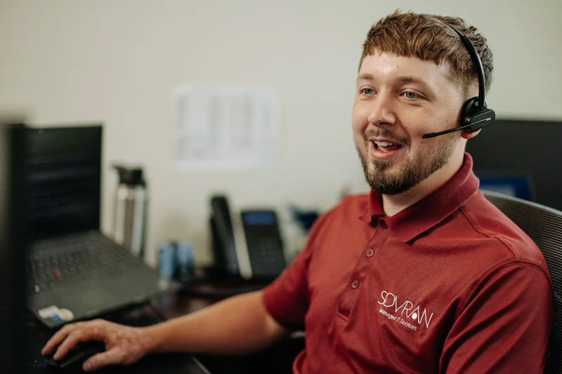 An IT helpdesk worker talking on a headset.