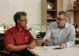 Two men at a desk reviewing options on a sheet of paper.