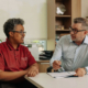 Two men at a desk reviewing options on a sheet of paper.