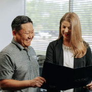 Two office workers looking at a folder together.