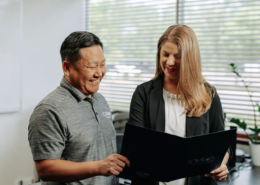 Two office workers looking at a folder together.