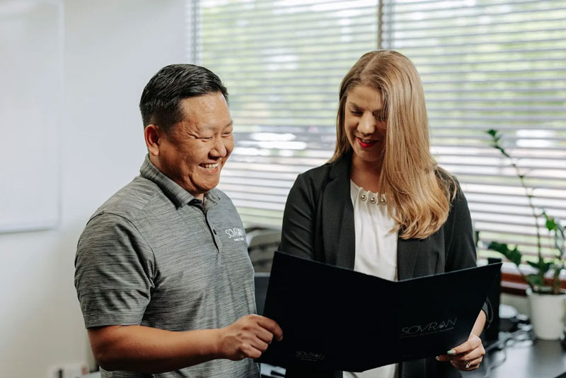 Two office workers looking at a folder together.