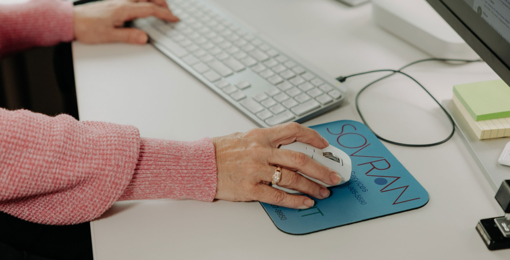 A woman using her computer mouse to view emails at work.