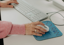 A woman using her computer mouse to view emails at work.