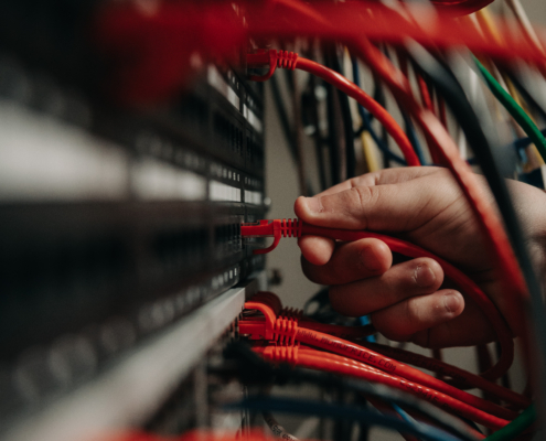 A worker plugs in a network cable to a server rack.