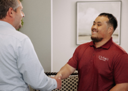Two IT workers shaking hands in an office.