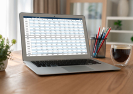 A laptop computer sitting on a table while displaying a spreadsheet.