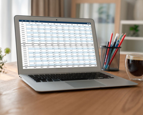 A laptop computer sitting on a table while displaying a spreadsheet.